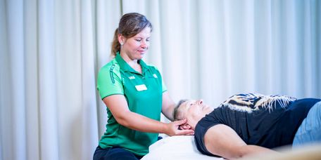 Therapeutin testet Beweglichkeit der Nackenmuskulatur