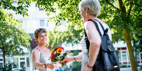 Besucherin überreicht Blumen an Patientin