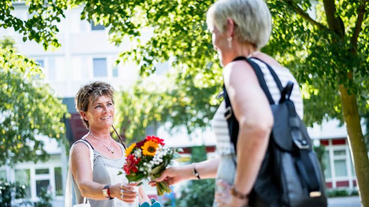 Besucherin überreicht Blumen an Patientin