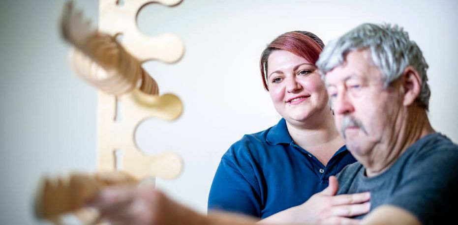 Ergotherapeutin übt mit Patient Feinmotorik