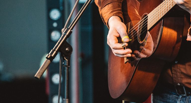 Musiker spielt Giarre auf der Bühne vor einem Mikrophone
