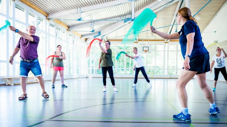 Patienten trainieren mit bunten Tüchern in der Bewegungstherapie