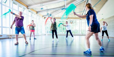 Patienten trainieren mit bunten Tüchern in der Bewegungstherapie