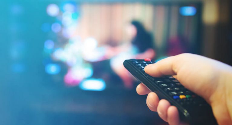 Mann schaltet Fernseher mit der Fernbedienung an