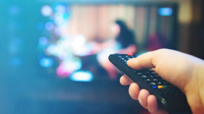 Mann schaltet Fernseher mit der Fernbedienung an