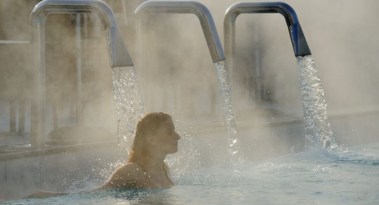 Junge Frau entspannt sich im Außenbecken eines Thermalbades