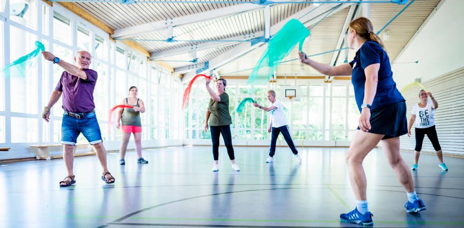 Patienten trainieren mit Tüchern in der Bewegungstherapie in der Sporthalle