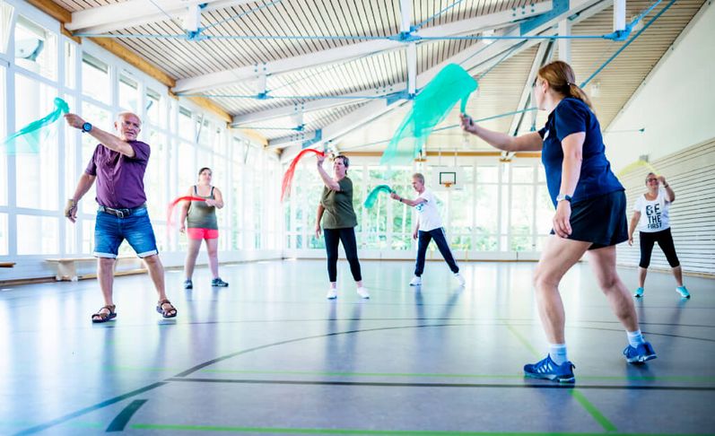 Patienten trainieren mit Tüchern in der Bewegungstherapie in der Sporthalle