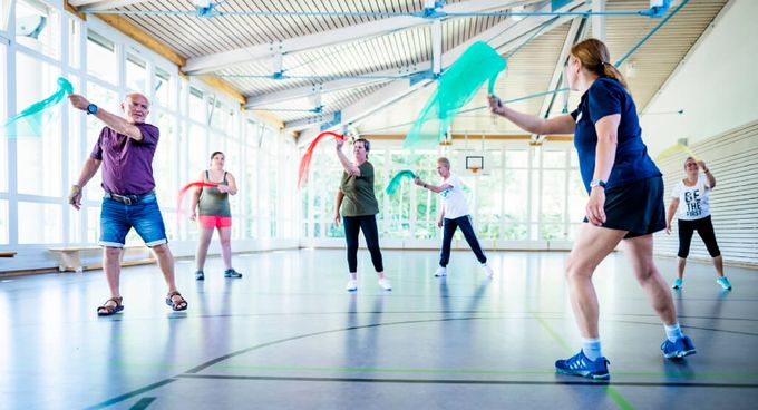 Patienten trainieren mit Tüchern in der Bewegungstherapie in der Sporthalle