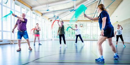 Patienten trainieren mit Tüchern in der Bewegungstherapie in der Sporthalle