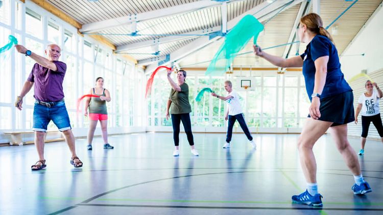 Patienten trainieren mit Tüchern in der Bewegungstherapie in der Sporthalle