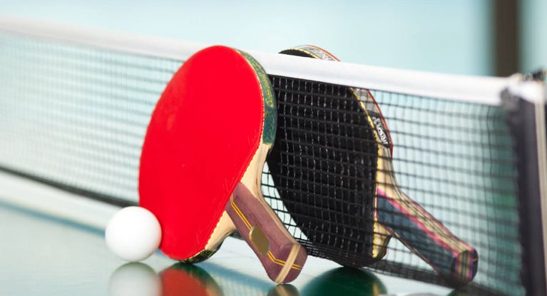 Tischtennisschläger lehnen am Netz der Tischtennisplatte