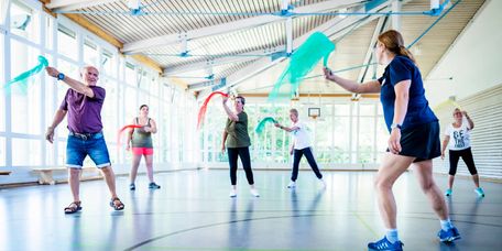 Patienten trainieren mit Tüchern in der Bewegungstherapie in der Sporthalle