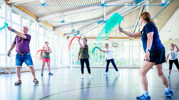 Patienten trainieren mit Tüchern in der Bewegungstherapie in der Sporthalle